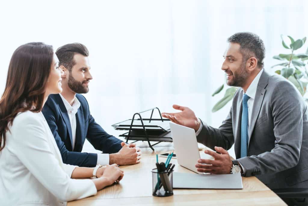 handsome advisor in suit talking with investors at workplace